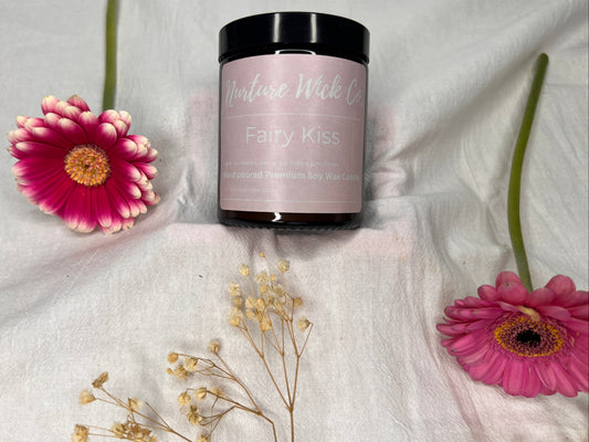 Jar of 'Fairy Kiss' product with pink flowers on a white fabric background