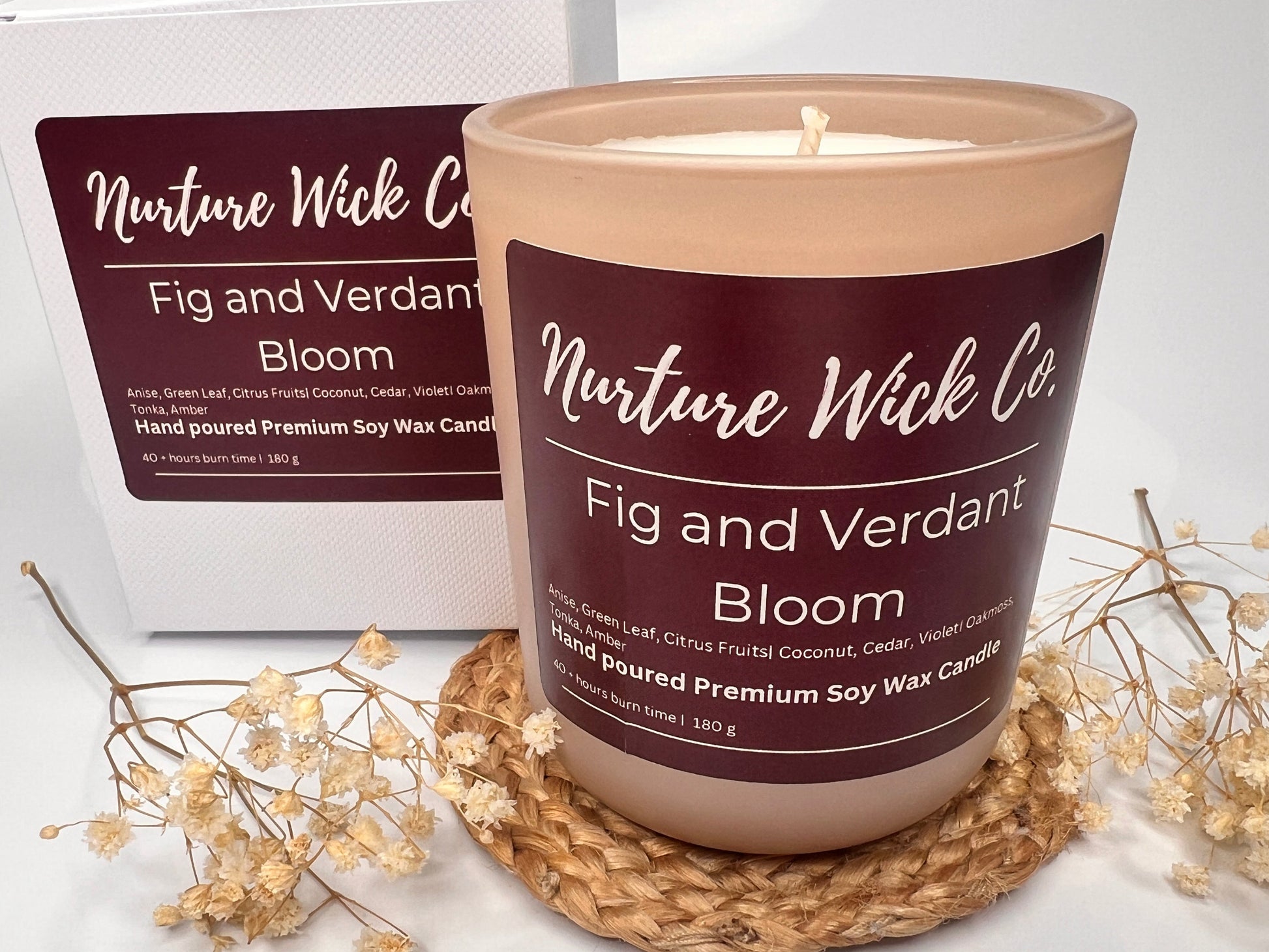 Nurture Wick Co. candle on a woven coaster with packaging in the background