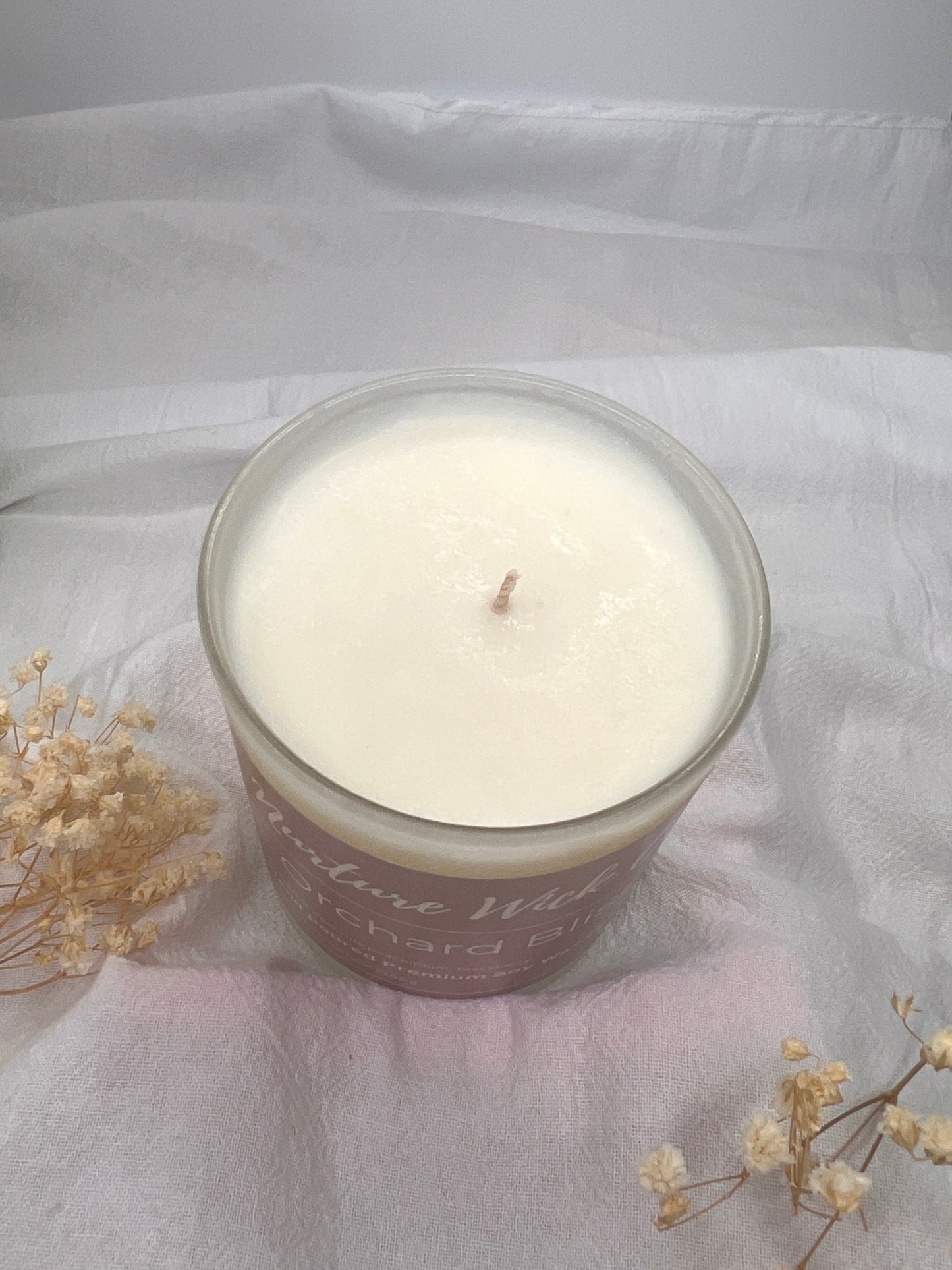 Candle in a glass jar with a decorative label on a light fabric background