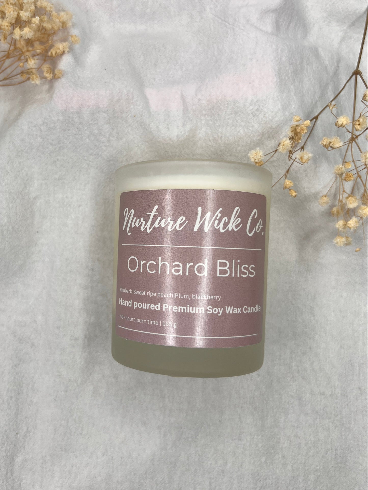 Candle with a purple label on a white fabric background