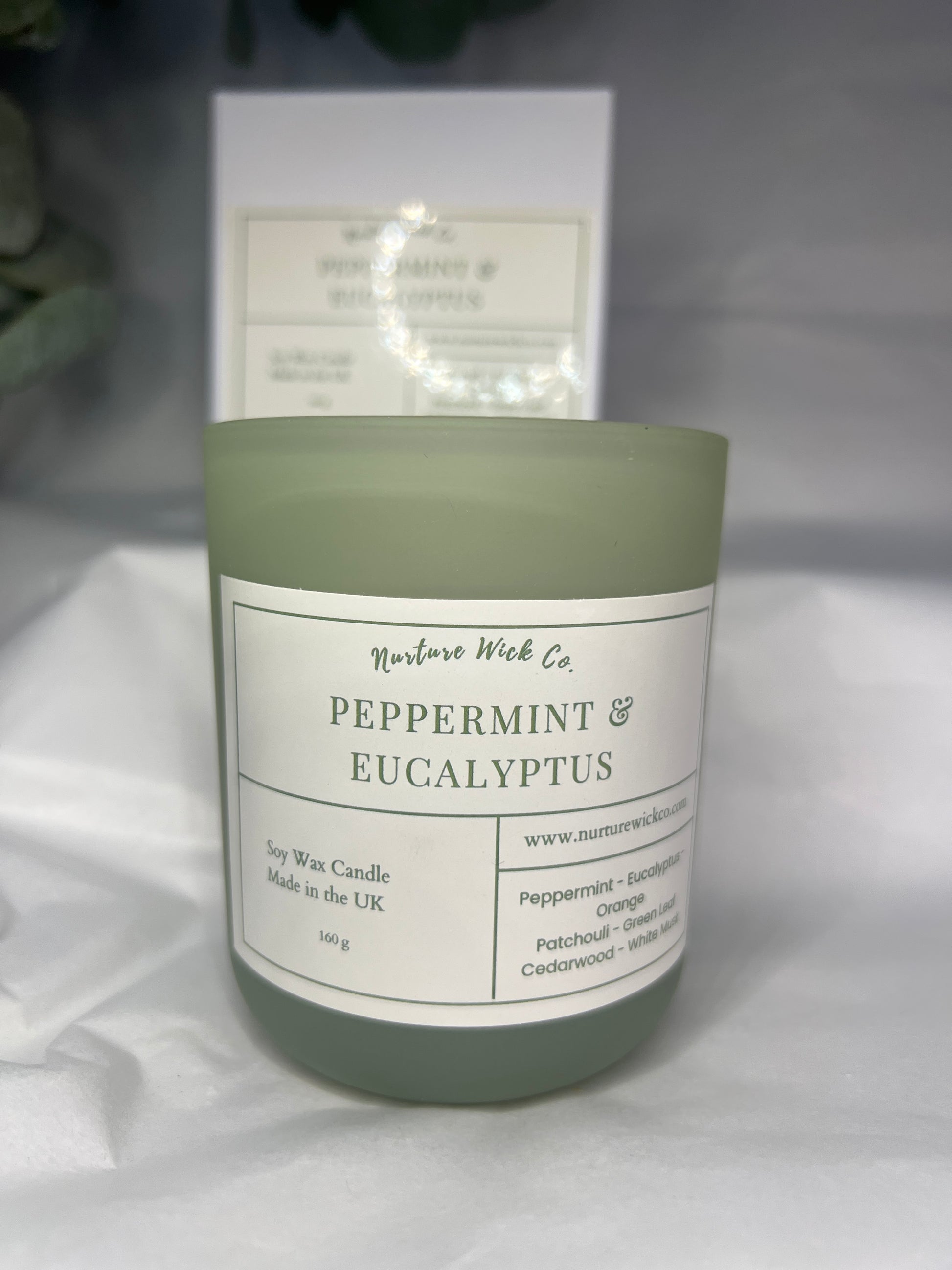 Green candle with a label on a white surface