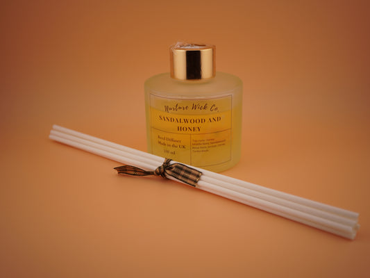 Sandalwood and honey diffuser with reeds on an orange background